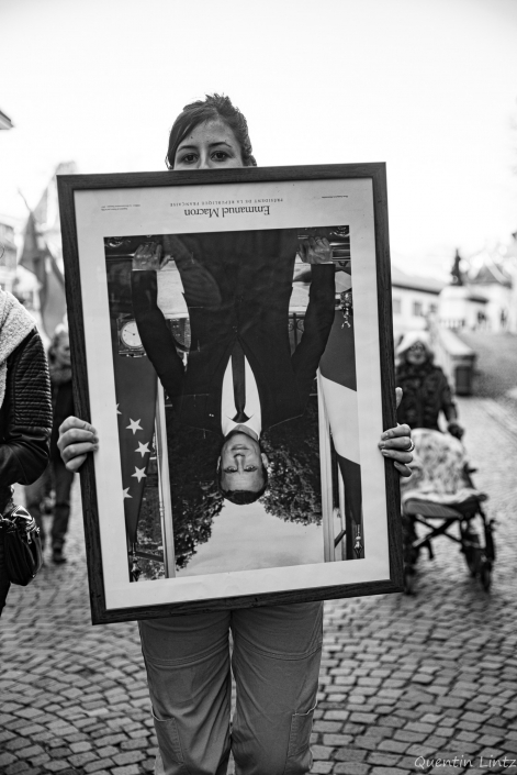 une manifestante tien le portrait de macron à l'envers