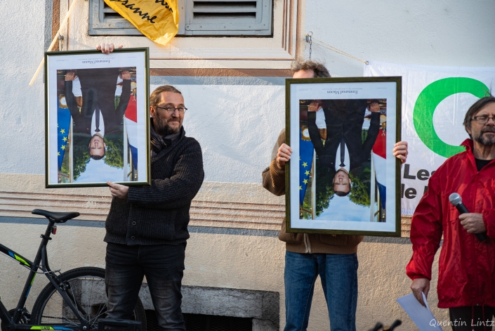 deux militant tiennent les portraits de macron à l'envers à coté de la préfecture de savoie à chambéry